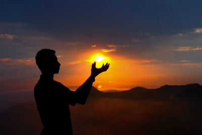 Silhouette man standing against orange sky