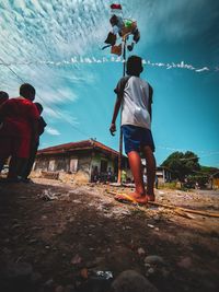 Rear view of people standing on land against sky