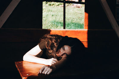 Young woman sitting on table by window