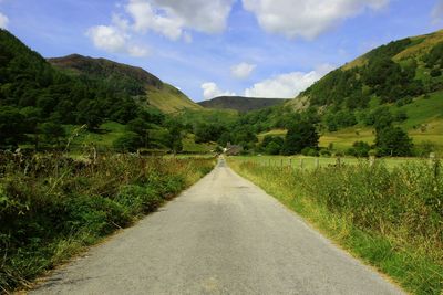 Road leading towards mountains against sky