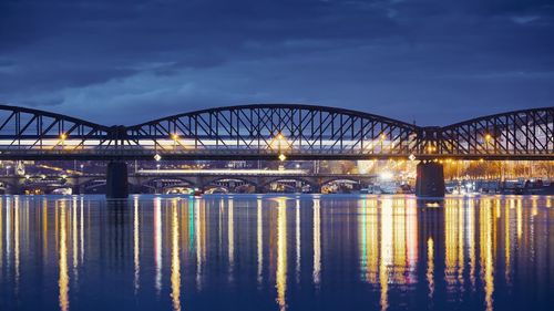 Illuminated bridge over river against sky at night