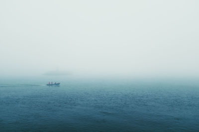 People on boat in sea against sky