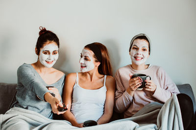 Women with facial mask sitting on sofa at home