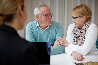 Smiling retired couple with female agent in real estate office
