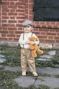 Portrait of boy with toy against wall