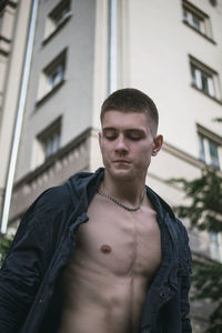 Portrait of young man standing against building