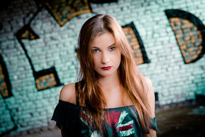 Portrait of young woman against graffiti wall on street