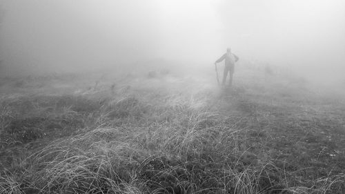 Man walking on field in foggy weather