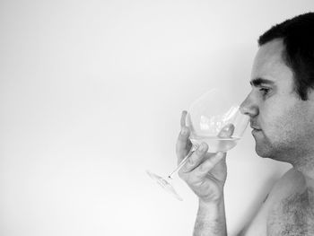 Man smelling drink against wall