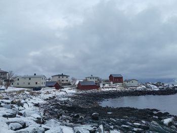 Buildings by sea against sky