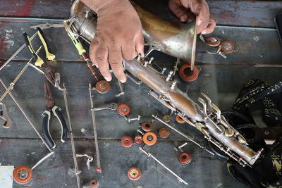 Cropped hands of man repairing musical instrument in workshop