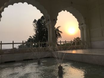 Fountain at lake during sunset
