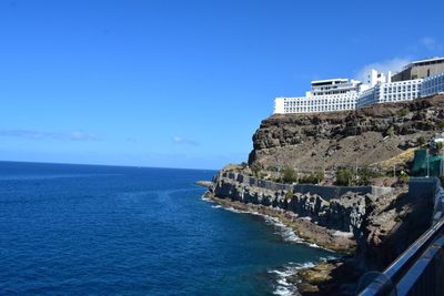 Scenic view of sea and buildings against blue sky