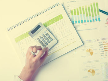 Cropped hand of businesswoman working with documents at desk