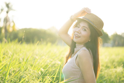 Portrait of smiling young woman wearing hat on field