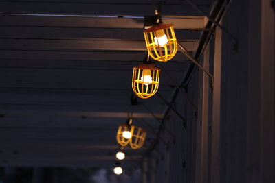 Low angle view of illuminated light bulb hanging at night