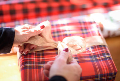 Cropped hands of woman wrapping gift at home