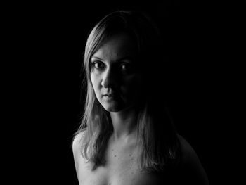 Portrait of young woman against black background