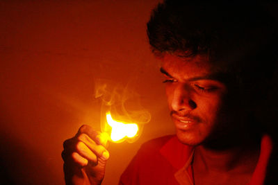 Close-up of young man holding lit matchstick