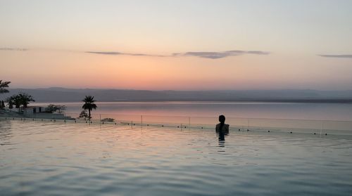 Rear view of woman in swimming pool during sunset