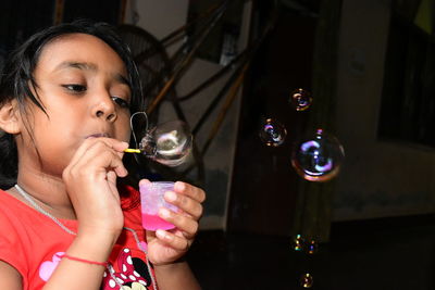 Girl blowing bubbles at home