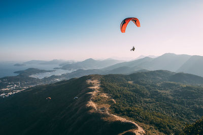 People paragliding over mountain against sky