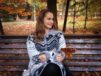 Woman in sweater sitting on a bench in autumn