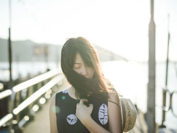 Young woman standing on pier during sunny day