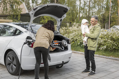 Parents loading pram into car boot