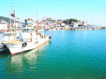 Boats moored at harbor against clear sky