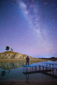 Rear view of man standing on mountain against sky at night