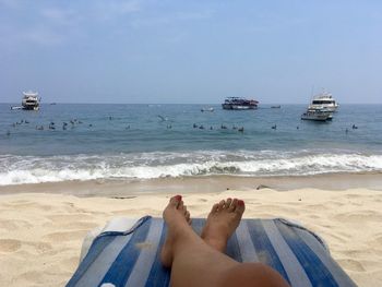 Low section of woman on beach against clear sky