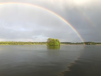 Scenic view of rainbow over lake against sky