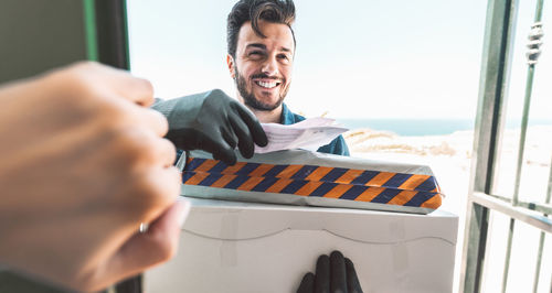 Smiling man holding paper at window