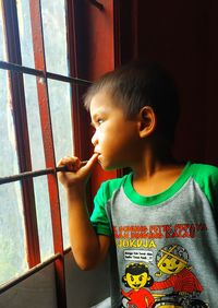 Cute girl looking through window at home