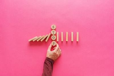 Midsection of person holding umbrella against pink background