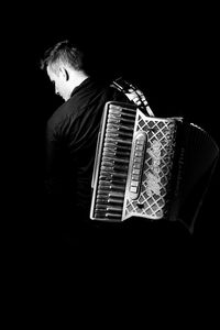 Low angle view of man playing against black background