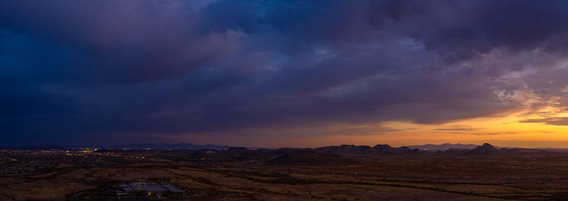 Scenic view of landscape against dramatic sky during sunset