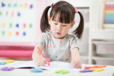 Young girl drawing on table at home