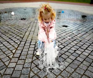 Full length of girl playing by fountain on city street