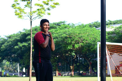 Portrait of young man standing against trees