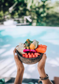 A woman is holding a healthy fruit bowl.