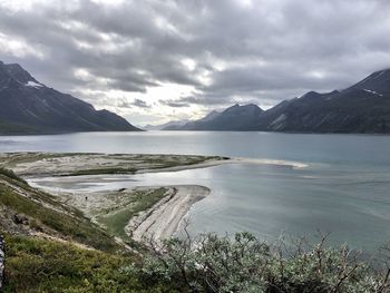 Scenic view of lake and mountains against cloudy sky