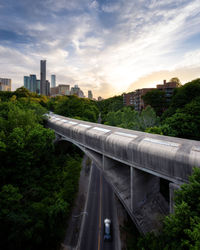 Railroad tracks by buildings in city against sky during sunset