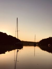 Silhouette sailboats in lake against sky during sunset