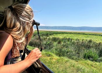 Close-up of woman looking through binoculars in jeep