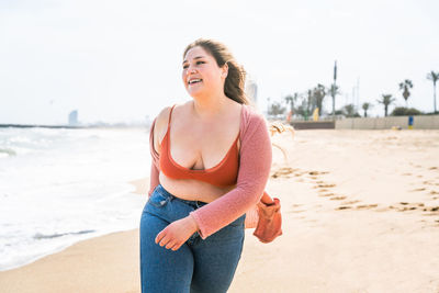 Young woman walking on sand against sky