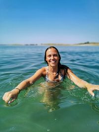 Portrait of a smiling young woman swimming in lake 