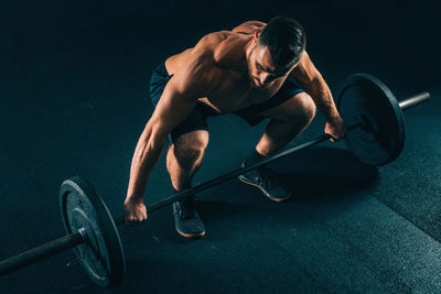 Male athlete exercising with barbell in gym