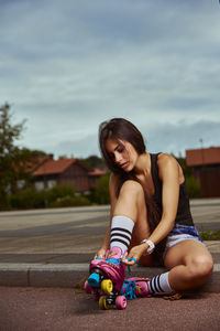 Young woman with skating shoe sitting outdoors